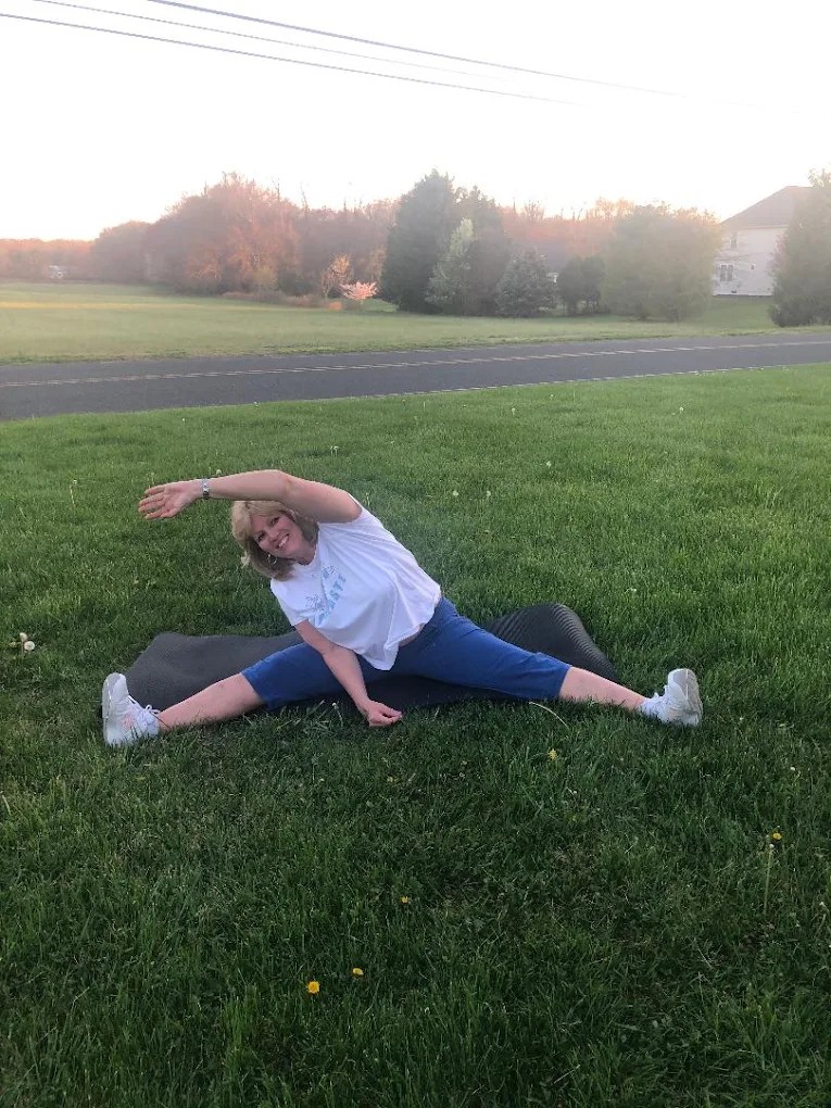 Christine stretching outdoors on a mat